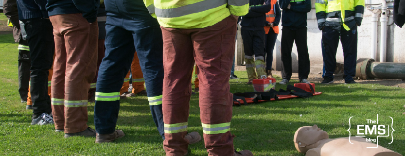 équipe-de-secouristes-en-tenue-réfléchissante-formée-autour-d-un-mannequin-de-premiers-secours