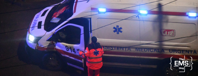 romanian-ambulance-with-flashing-blue-lights-and-a-paramedic-standing-beside-it-at-night